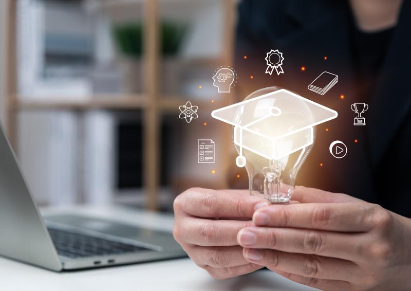 Illustrative image of person holding a light bulb with icons floating around it over an academic mortar board