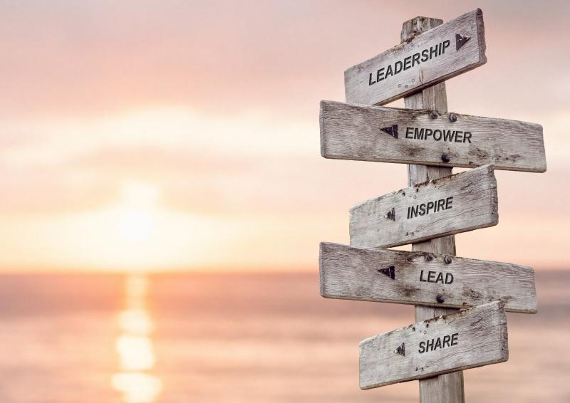 The words Leadership, Empower, Inspire, Lead and Share displayed on a Wooden sign.