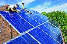 Image of a rooftop with solar panels and an installer fixing them. Image courtesy of Chris Oaten