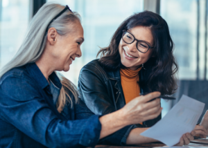 Image of two people sitting and smiling looking at a report