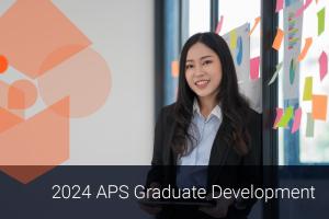 A confident young female graduate stands next to an office window