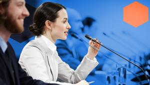 Two people sitting at a desk in front of a microphone